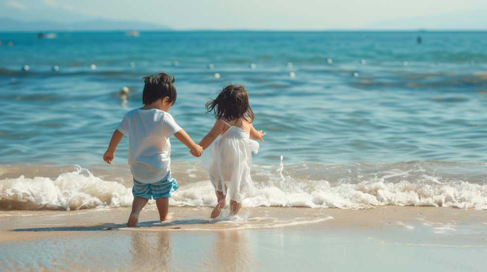 夏の浜辺を歩く幼い兄妹の後ろ姿
